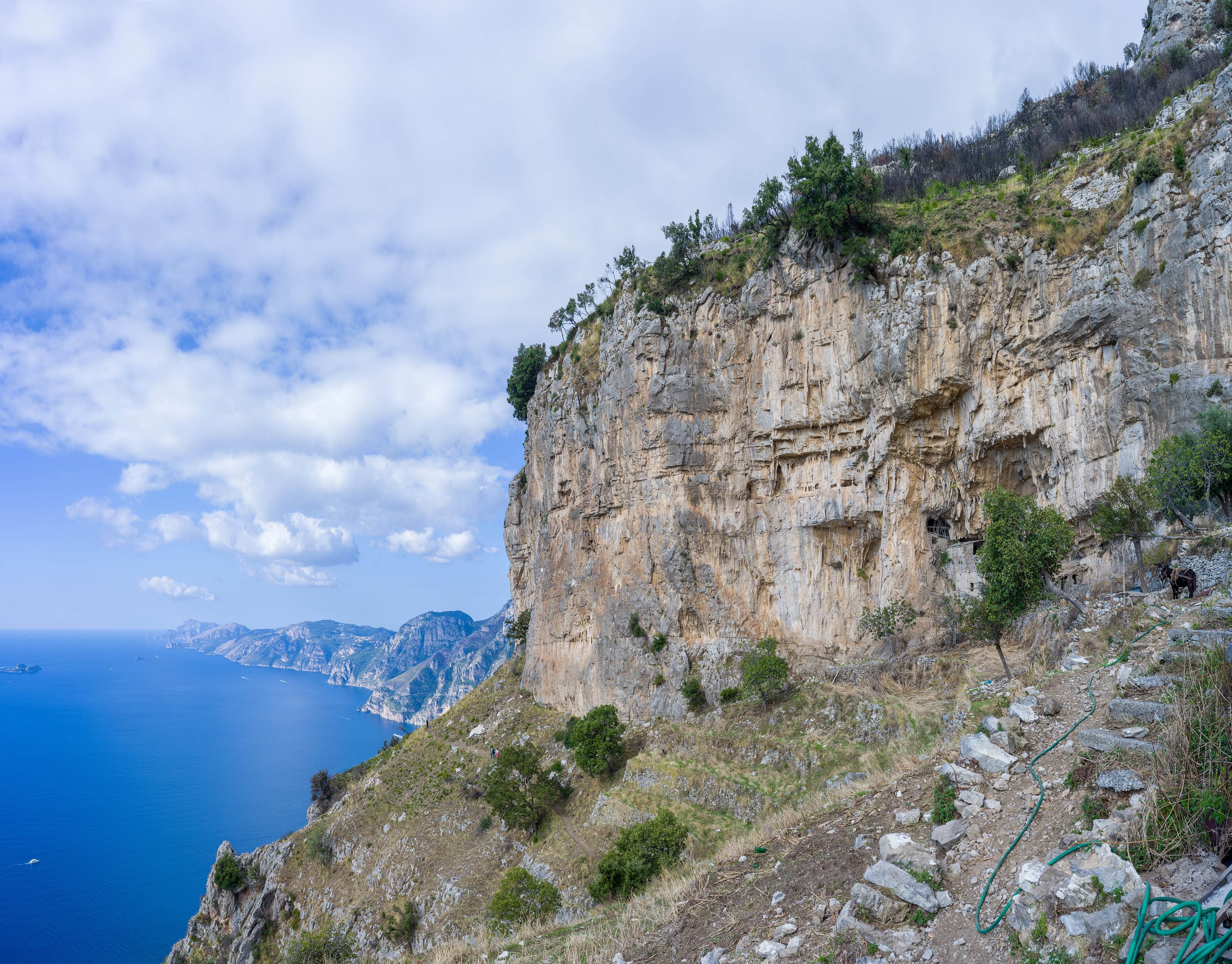 The trail passing beneath a tall limestone cliff face