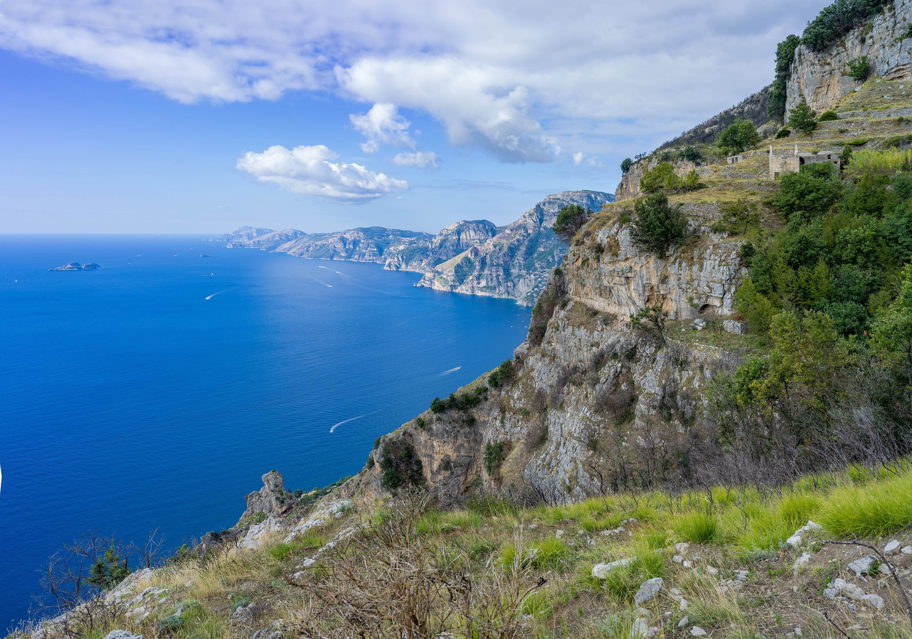 Limestone cliffs dropping to a deep blue sea, seen from the trail